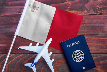 Flag of Malta with passport and toy airplane on wooden background. Flight travel concept
