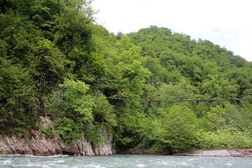 Suspended wooden bridge over a mountain river.