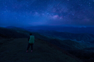 Colorful night sky with stars and silhouette of a standing man on the stone. Blue milky way with man on the mountain. High Rocks. Background with galaxy and silhouette of a man. 