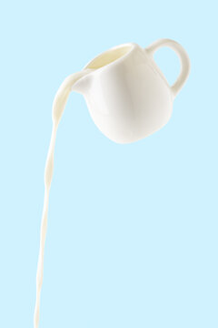 pouring milk from milk jug isolated on blue background