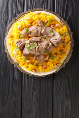 Mansaf is a traditional Arab dish made of lamb cooked in a sauce of fermented dried yogurt and served with rice closeup in the plate on the table. Vertical top view from above