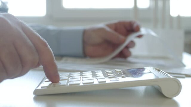 Businessman Working with Invoices, Makes Financial Calculations with Adding Machine. Accounting Fee and Taxes Calculations.