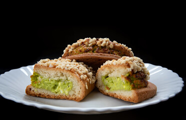 Delicious sliced pastries with pistachio curd and nuts on a white plate.