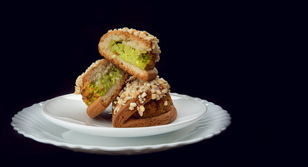 Delicious sliced pastries with pistachio curd and nuts on a white plate.