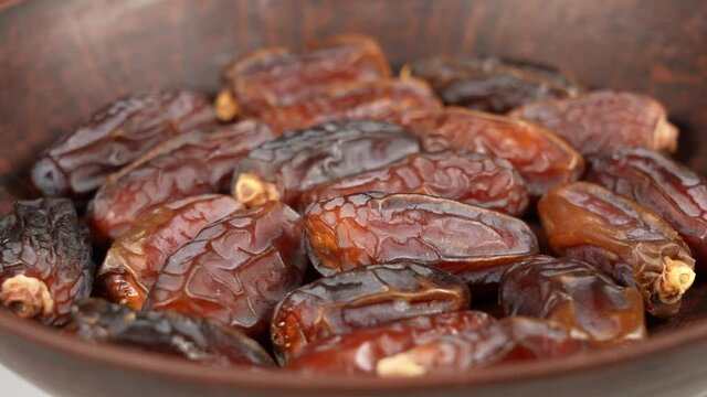 Close-up 4K video footage of tasty brown dried dates fruit isolated in brown bowl background