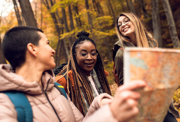 Three female friends enjoying hiking in forest on a beautiful autumn day.	