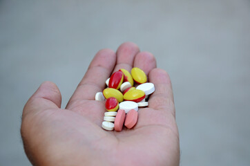 closeup bunch the pink ,white with red,yellow color small medicines tablet, capsule hold hand health care medical concept isolated on brown background.