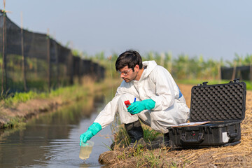 Man technician in full body protective suit collecting sample of water .Portable water quality measurement .Water quality for agriculture. Checking water ph on field.