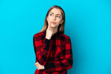 Young caucasian woman isolated on blue background having doubts while looking up