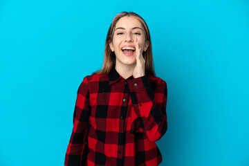 Young caucasian woman isolated on blue background shouting with mouth wide open