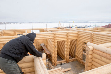 Carpenter works at the construction of wooden house