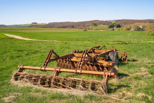 Old rusted tractor plow with wheels on the meadow