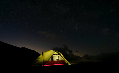 Wild camping tent at night under stary sky in the mountains