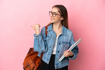 Young caucasian student woman isolated on pink background pointing to the side to present a product