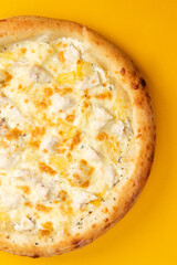 Pizza with cheese and pineapple on a yellow background.