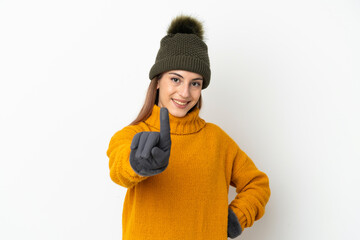 Young girl with winter hat isolated on white background showing and lifting a finger