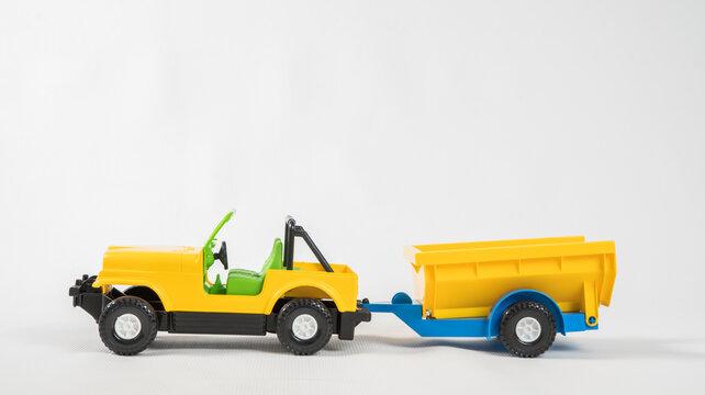 Plastic toy multicolored cars isolated on white background. SUV with a trailer.