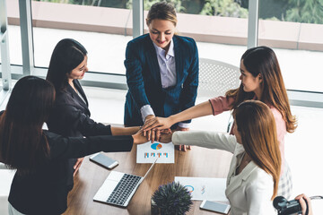 Businesswomen joining hands in group meeting at modern office room showing teamwork, support and...