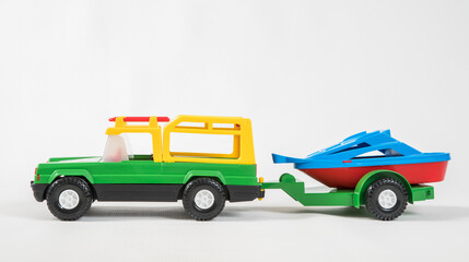 Plastic toy multicolored cars isolated on white background. SUV with a trailer.