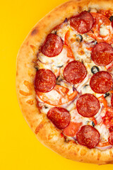 Pizza with pepperoni and tomato. On a yellow background.