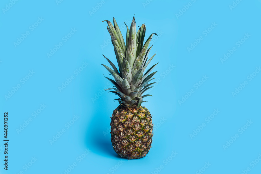 Wall mural Vertical picture of fresh ripe pineapple on a blue background