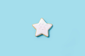 Cookies in the form of a star with icing painted a face on a blue background. Top view, flat lay.
