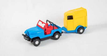 Plastic toy multicolored cars isolated on white background. A car with a van for transporting horses.