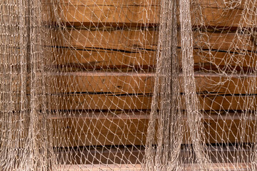 Wooden brown walls of the house covered with the fishing net, old and grange style. Abstract decoration. 