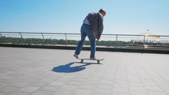 A young millennial guy who rides a skateboard carefree in the city.Young attractive guy is riding a skateboard. A professional skateboarder rides a skateboard along the city embankment. The