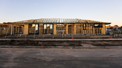 A side on profile at sunset of a house during the frame stage of construction. Some windows...