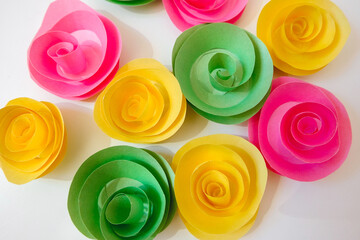 Delicate variegated homemade spiral paper flowers, similar to roses. View from above. Celebration concept