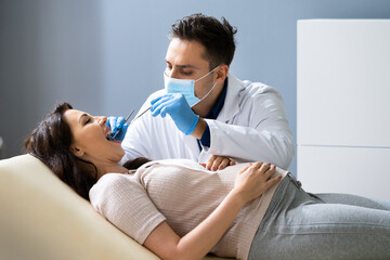 Dentist Treating Teeth Of Pregnant Woman Patient Lying