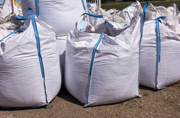 Several large, filled waters, ready for removal, stand by the road,