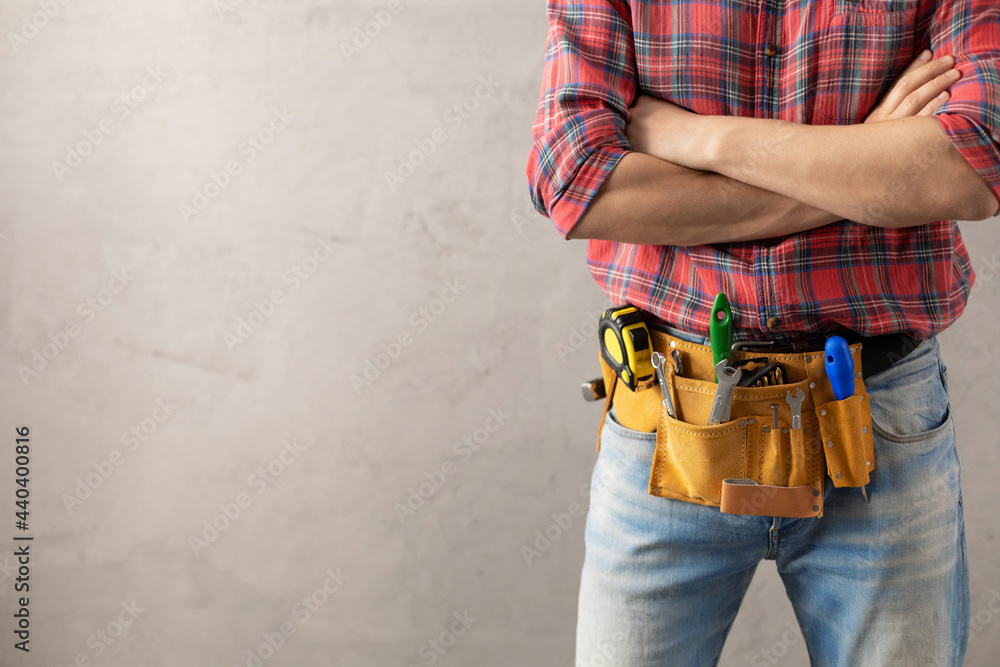 Wall mural man worker and tool belt near wall. male hand and construction tools. renovation concept