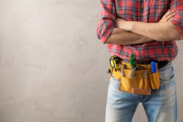 Man worker and tool belt near wall. Male hand and construction tools. Renovation concept