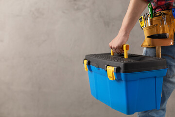 Man worker holding toolbox and tool belt near wall. Male hand and construction tools - 440400838