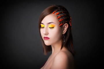 Beautiful girl on a monochrome studio background with bright makeup. Woman with pigtails from the side.