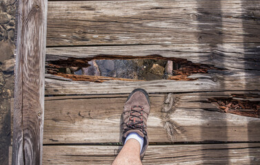 Trekker walking over broken wooden bridge - obrazy, fototapety, plakaty