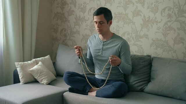Man meditates on a beads at home