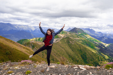 cheerful young woman after a successful Hiking fun jumps on the top of the mountain.