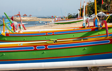 Fototapeta na wymiar Brightly painted fishing outriggers on the beach at Sanur, Bali, Indonesia