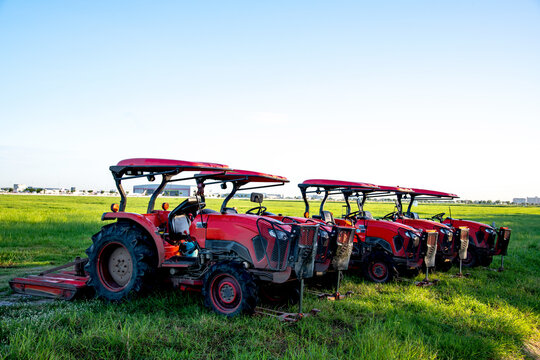 Red tractors parking in a grass field with blue sky background.
