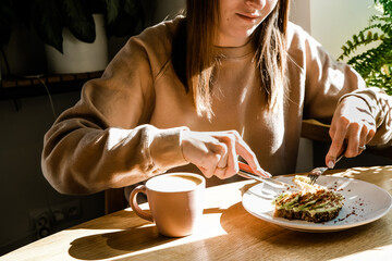 Young woman enjoying in taste, drinking coffee while taking avocado bruschetta breakfast