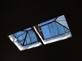 Old broken skylight in abandoned factory. Sunshine blue sky beyond dirty cracked glass. - 440406865