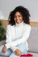 Attractive young african american woman wrapped in christmas lights and smiling. Christmas mood concept.