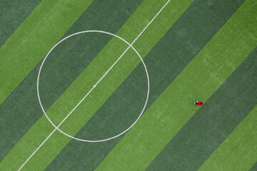 Obraz premium Top view of a person standing on a green lawn in the center of a football field