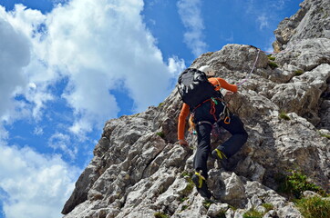 Klettern am Berg im steilen Fels mit Helm, Rucksack und Seil.