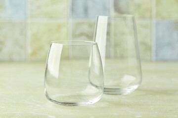 Two empty glasses for water or cocktails on light table. Glasses cup for drinks. Beverage concept