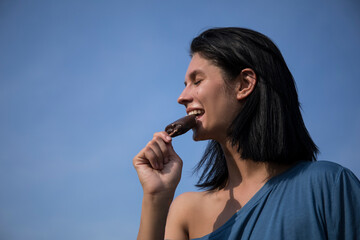 Beautiful young woman eating ice cream. Sensual. Ice cream. Sky background. Photo. 