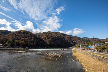 People crossing the Togetsu-kyo Bridge over the Oi River in the Arashiyama District of Kyoto, Japan.